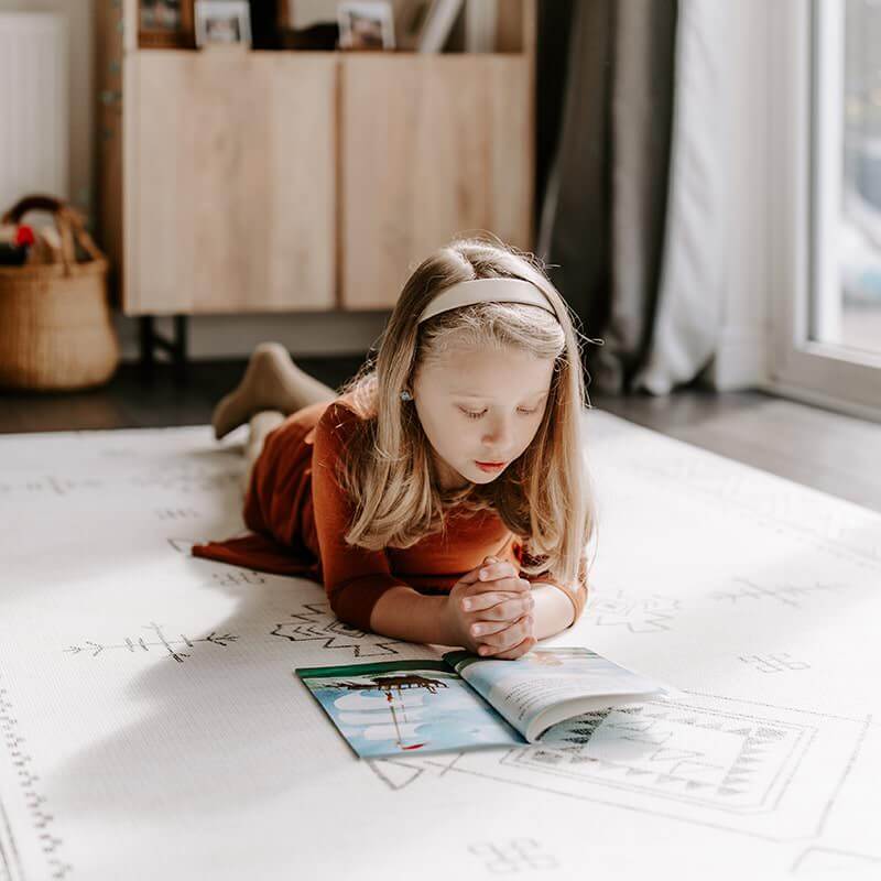 Girl reading on the Dakota Ivory Shwally Playmat in a neutral room