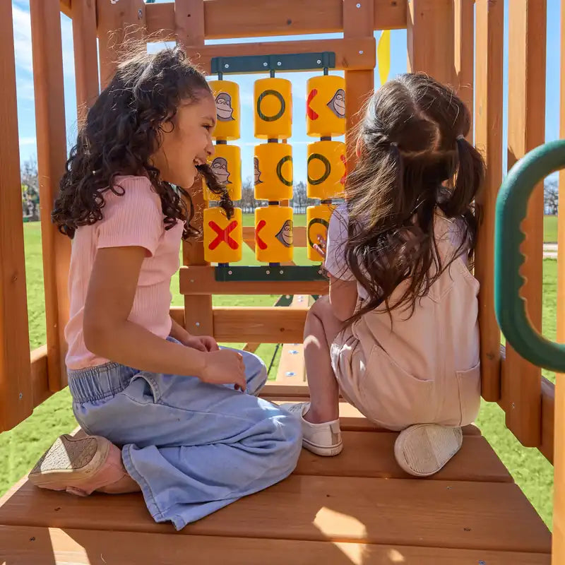 Gorilla Playsets Summerville Deluxe Swing Set – children playing tic-tac-toe inside the clubhouse