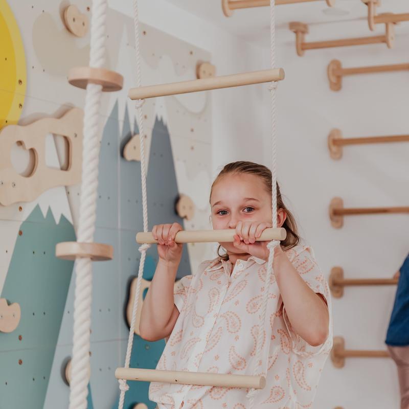 Kids Climbing Ropes – kid gripping a wooden rope ladder rung