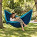 Colibri 3.0 River - Double Travel Hammock with Suspension – lifestyle illustration of adult relaxing in the travel hammock between trees