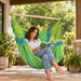 Domingo Lime - Weather-Resistant Kingsize Hammock Chair – lifestyle illustration of adult reading in the hammock chair on a patio