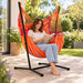Fiji Outdoor Toucan – Weather-Resistant Basic Size Hammock Chair with Galvanized Steel Stand – lifestyle illustration of adult reading in the hammock chair on a patio