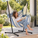 Fiji Outdoor Sea Salt – Weather-Resistant Comfort Size Hammock Chair with Galvanized Steel Stand – lifestyle illustration of adult reading in the hammock chair on a patio