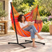 Fiji Outdoor Toucan – Weather-Resistant Comfort Size Hammock Chair with Galvanized Steel Stand – lifestyle illustration of adult reading in the hammock chair on a patio