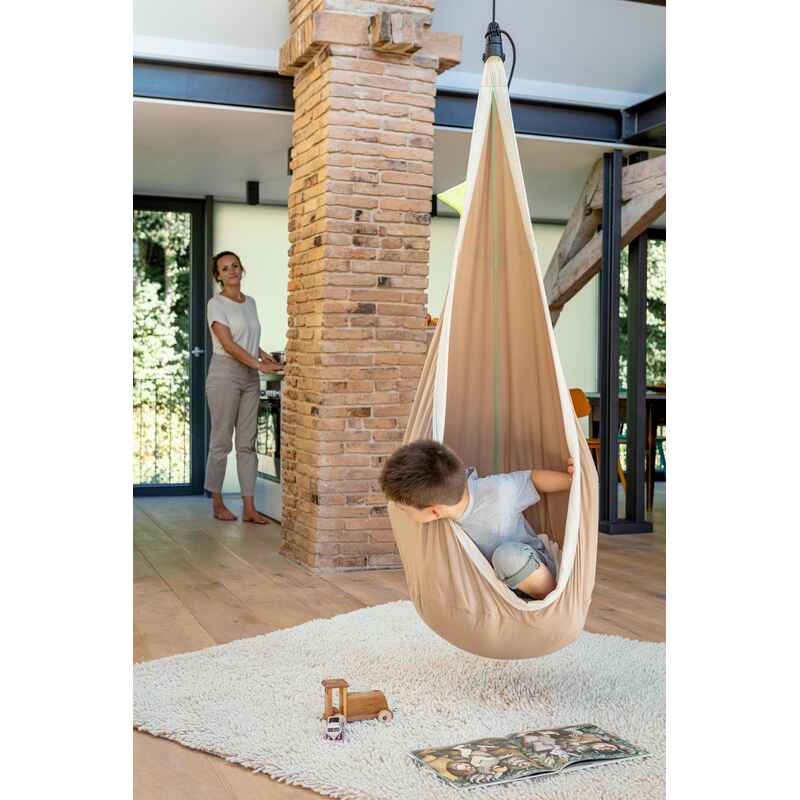 LA SIESTA Joki Teddy Kids Hanging Nest – kid reclining beside a brick column