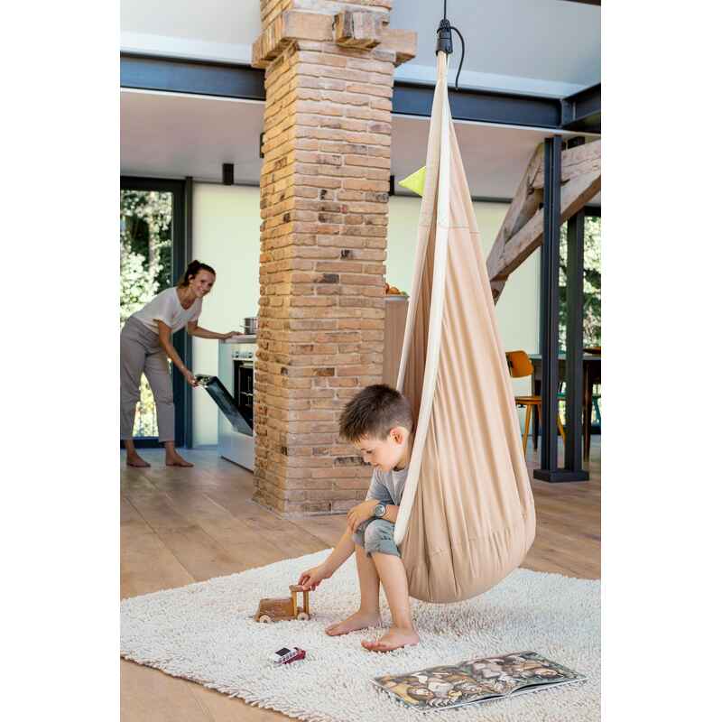 LA SIESTA Joki Teddy Kids Hanging Nest – nest beside a brick column with an adult nearby