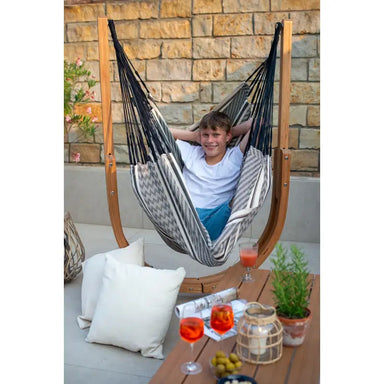 Udine Organic Zebra - Organic Cotton Hammock Chair with FSC® certified Eucalyptus Stand – person seated against a stone wall