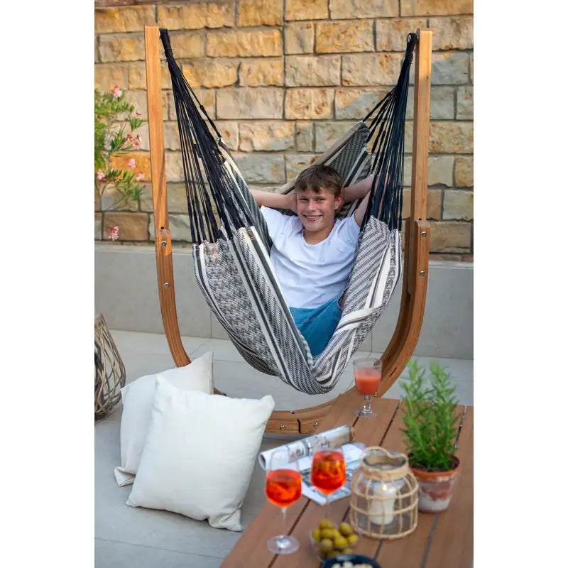 Udine Organic Zebra - Organic Cotton Hammock Chair with FSC® certified Eucalyptus Stand – person seated against a stone wall