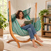Udine Organic Agave - Organic Cotton Hammock Chair with FSC® certified Eucalyptus Stand – lifestyle illustration of adult reading in the hammock chair in a family reading room