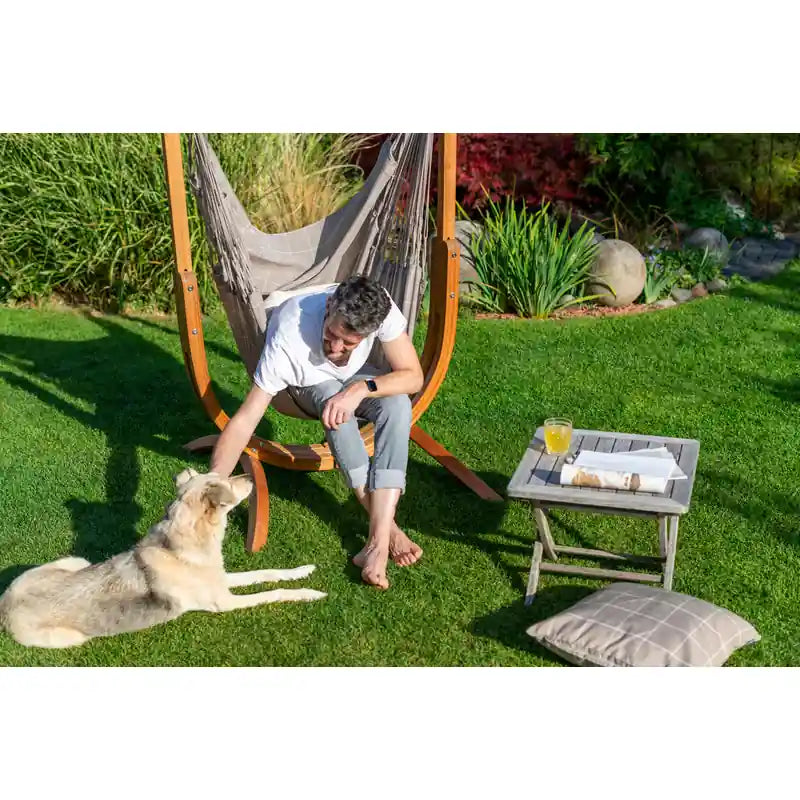Udine Outdoor Almond - Weather-Resistant Hammock Chair with FSC® certified Eucalyptus Stand – person petting a dog from the chair