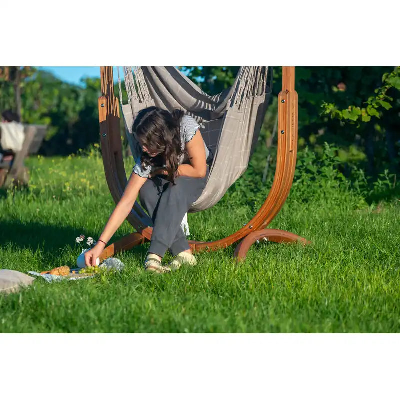 Udine Outdoor Almond - Weather-Resistant Hammock Chair with FSC® certified Eucalyptus Stand – person reaching from the chair toward a picnic