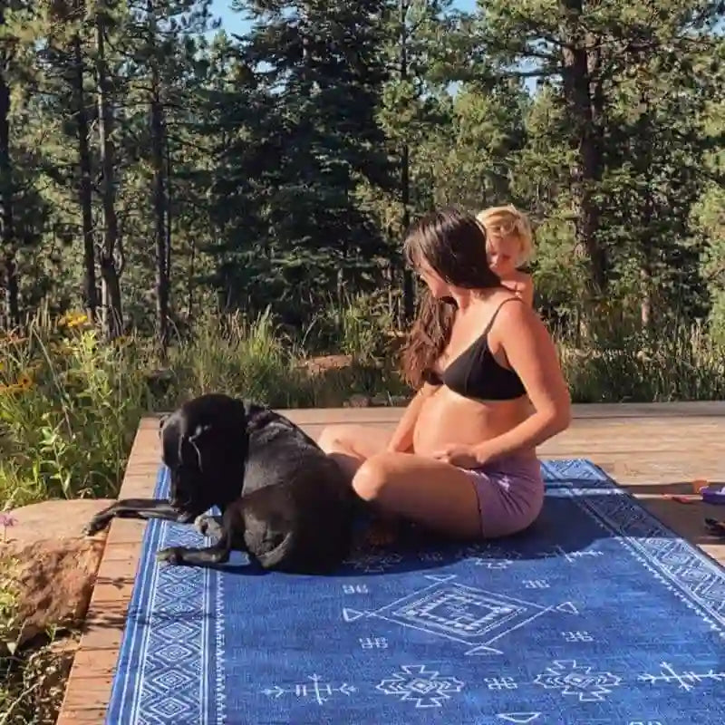 Woman and dog relaxing outdoors on the waterproof Dakota Blue Shwally Playmat