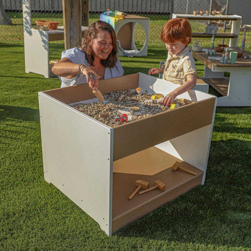 Outdoor sensory table with a teacher and student playing 