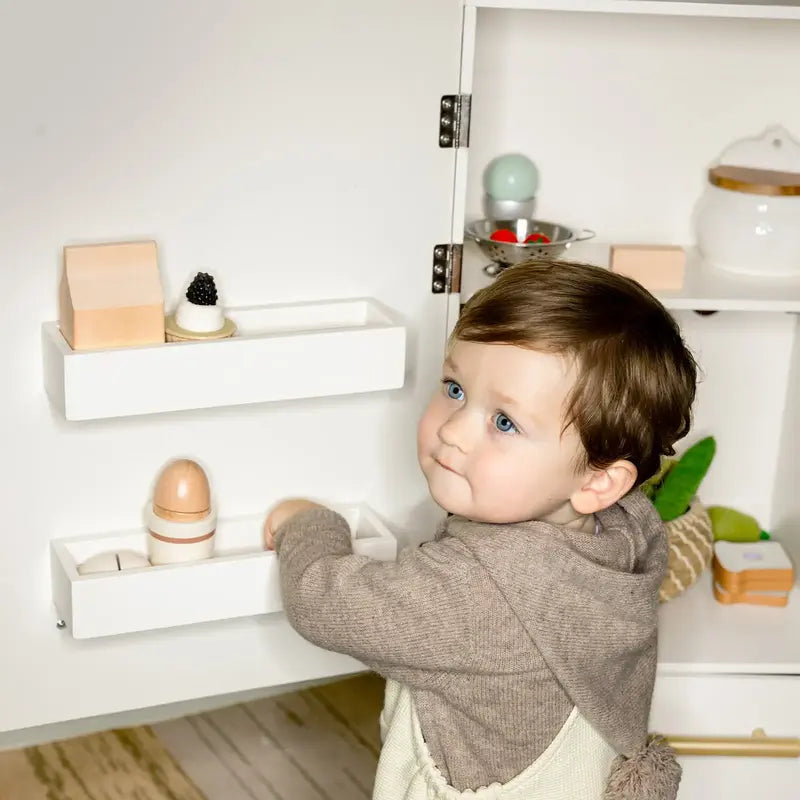 Tiny Land® Play Kitchen Accessories – Play Kitchen Fridge: Wooden Cabinet Refrigerator for Kids – Child placing toy eggs in an inside-door storage bin