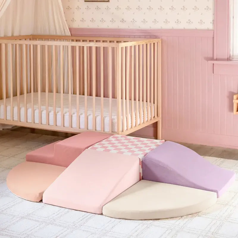 Tiny Land® PlayNest Climbing Blocks - Violet – Violet foam climbing blocks arranged on a rug beside a crib